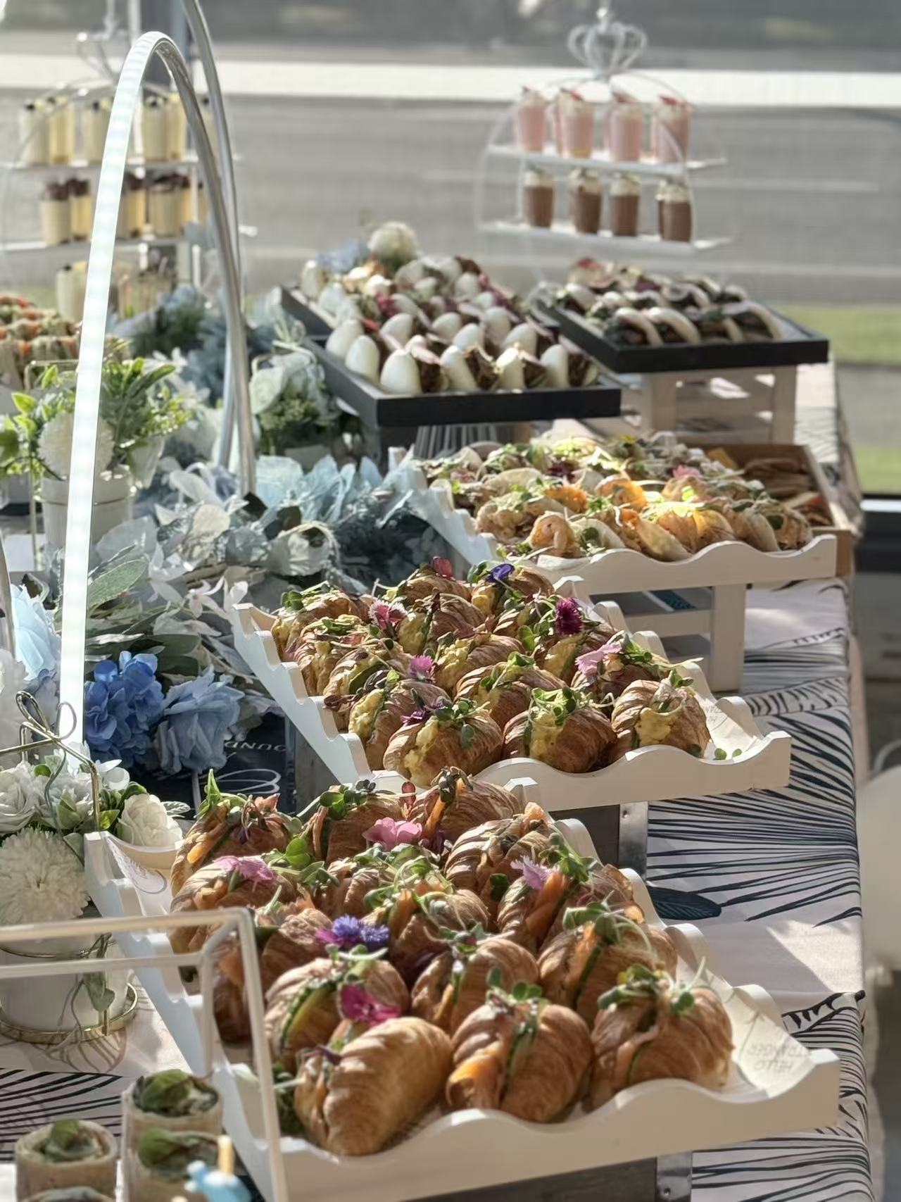 Long buffet of filled croissants, bao and dessert shots