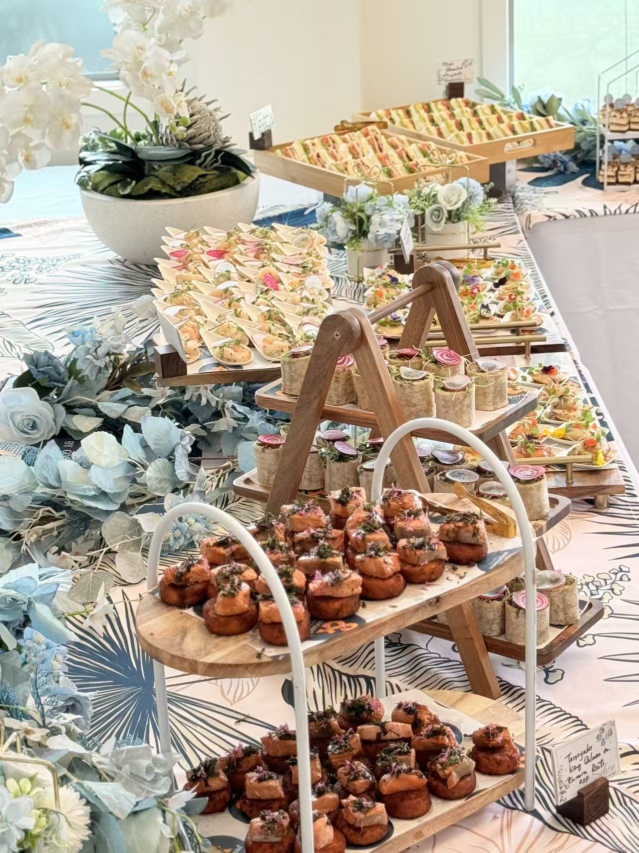 Salmon rosti canapés and mini wraps on wooden tiers